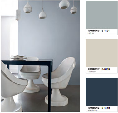 déco Salle à manger design avec une peinture murale gris clair associée au gris béton du sol. Table peinte couleur noir, chaises blanches 