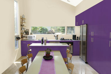 Peinture cuisine  en L avec ilot central, meubles  finition laquée violet associée à une peinture mural couleur lin dese Peintures Julien. La table de ferme reprend ces deux couleurs avec nappe en lin et un chemin de table parme