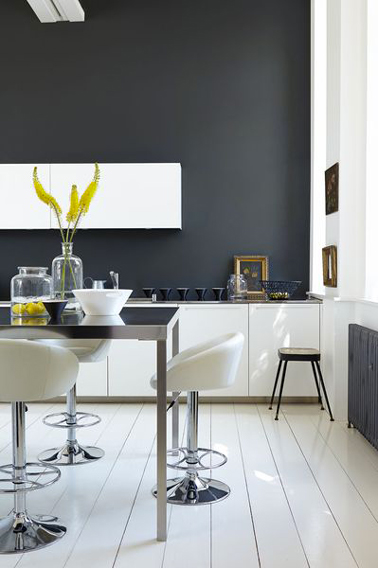 Sur un des murs d'une cuisine blanche de style moderne, une peinture gris anthracite est une bonne façon de dynamiser l'ambiance en utilisant les contrastes.