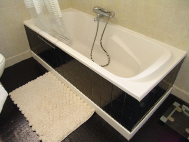 La peinture carrelage salle de bain un petit bijou ! Une salle de bain entièrement relookée avec une peinture carrelage aspect satin noir sur le tablier baignoire et un enduit décoratif gris sur faïence murale protégé des projections d’eau par un vernis bateau incolore.