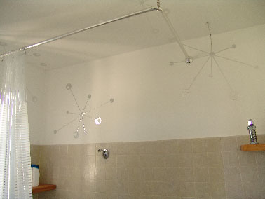 Pour relooker cette salle de bain devenue vieillotte on a utilisé une peinture carrelage aspect béton gris perle sur la faïence murale au dessus de la baignoire puis placé quelques pastilles stickers effet miroir dénichés dans les rayons de Leroy Merlin