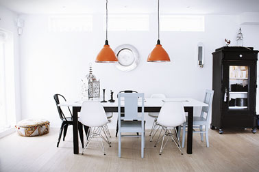 Espace salle à manger d'un style industriel avec chaises dépareillées bois gris, metal noir et coque blanche