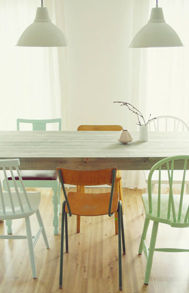 Salle à manger avec table en bois cérusé et ensemble de chaises en bois dépareillées. Harmonie de vert jade, vert céladon et chaises laissées en bois brut 