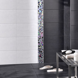 Carrelage douche à l’italienne noir carreaux de 25X40 cm souligné d’un listel en verre teinté posé à la verticale pour délimiter la zone de la douche. Carrelage mural Vario chez Lapeyre.