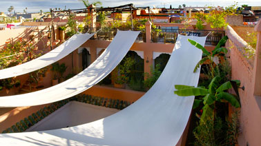 Brise-soleil réalisé avec des bandes de toile blanche sur une terrasse ambiance méditéranéenne