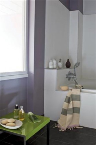 Dans cette petite salle de bain, une peinture couleur parme dynamise le blanc du carrelage et la petite table est repeinte en vert avocat pour apporter un contrat  tonique