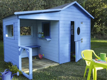 cabane de jardin en bois pour enfant avec terrasse abritée. Murs bois extérieur peints couleur bleu azur, petit salon de jardin en plastique vert