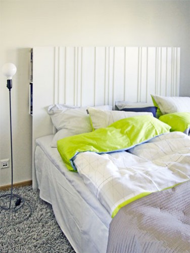 Une tête de lit en médium qui intègre des rangements fabriquée sur le modèle bien connu d'Ikéa. Le panneau de médium repose sur deux rangées de casiers fixés au mur. Les casiers de rangement se trouvent pour un prix modique