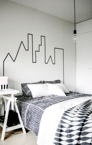 Sur les murs peints en blanc, la tête de lit est matérialisée avec un dessin reprenant les contours d'un château réalisé avec un ruban adhésif noir.