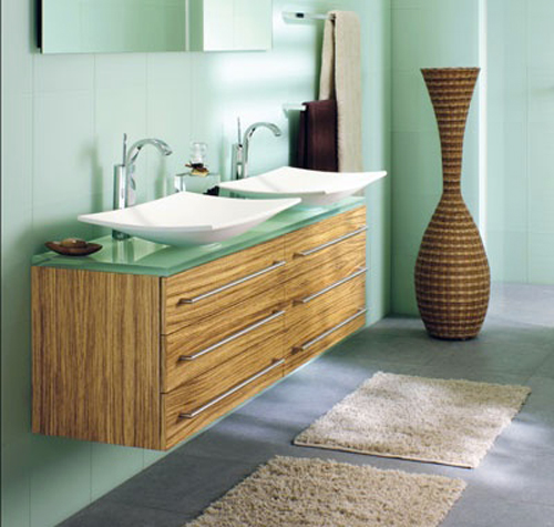 Des couleurs tendres pour une salle de bain nature et zen. Vert d'eau pour le carrelage mural et le plan de travail en verre fumé associé à un meuble lavabo chêne clair. Deux vasques couleur ivoire pour rester dans la même gamme de tons.