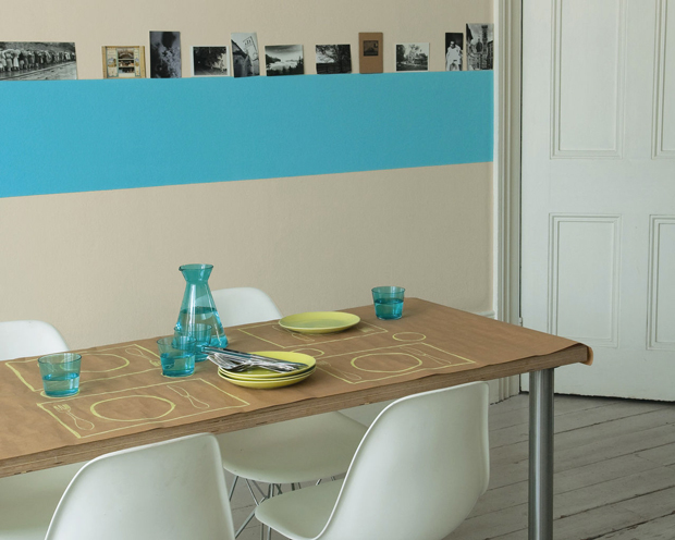  Pour agrandir visuellement l'espace repas dans le salon qui s'harmonise entre deux couleurs de peinture lin, une bande de bleu turquoise est peinte sur le mur le moins large. 