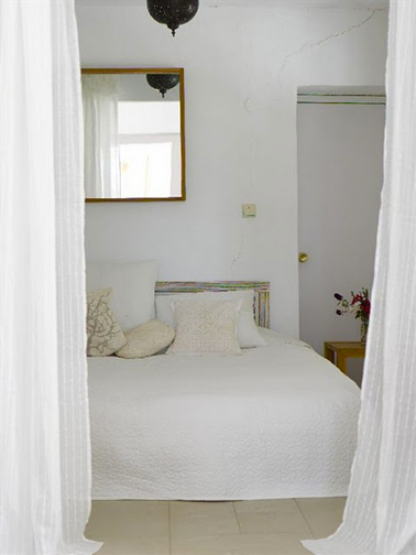 Couleur chambre beige et blanche. Peinture blanc mat, porte peinte en beige. Tête de lit en bois clair, carrelage au sol grès beige, coussins ivoire, légèreté des rideaux en voile blanc cassé. 