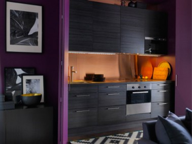 Cuisine noire ouverte sur salon. Peinture prune et crédence verre orange. Modèle cuisine Gnosjo chez Ikéa