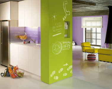 couleur vives pour un salon ouvert sur cuisine Salon et cuisine dans loft couleur peinture vert pomme et parme. carrelage sol couleur lin. La crédence en verre fait un rappel de couleur avec le parme du salon