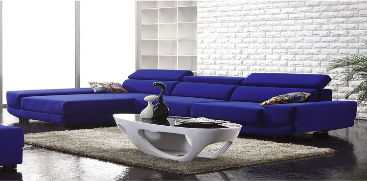 En bleu et blanc le design s'invite dans le salon. Le canapé bleu roi constitue l'élément fort du salon autour des matériaux bruts des murs en brique blanche et du sol béton peint en noir