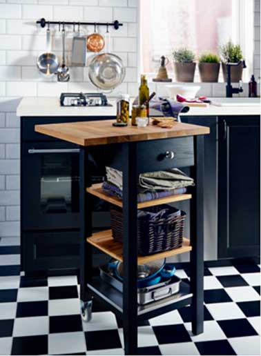 Dans une cuisine noire agrandie par un carrelage sol en damier noir et blanc, un rangement supplémentaire avec une desserte 2 tablettes réglables en chêne massif et porte bouteilles Ikea.