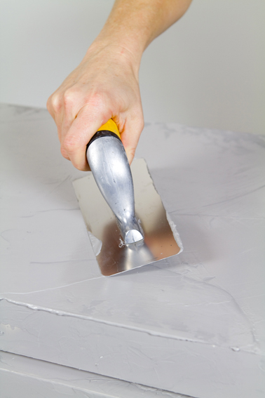 Appliquer le béton ciré en couche épaisse sur le meuble à l'aide d'une taloche en inox. Temps de séchage : 4 heures