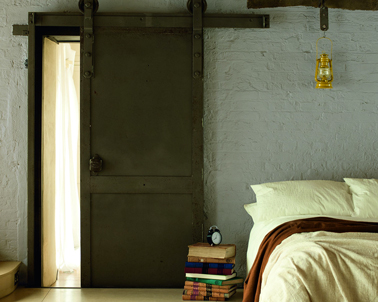 Peinture couleur gris perle sur les murs de brique d'une chambre pour adoucir le brun foncé des poutres et de la porte en chêne 