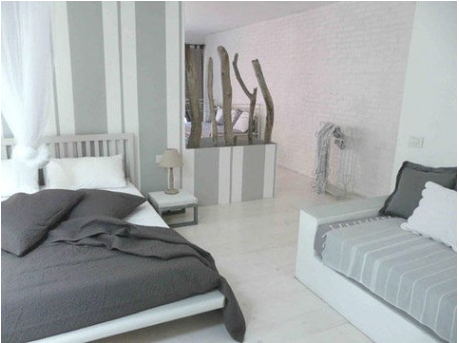 Déco chambre gris : Banquette couleur gris et blanc, tête de lit bois blanc, lampe de chevet et table de nuit couleur gris perle.