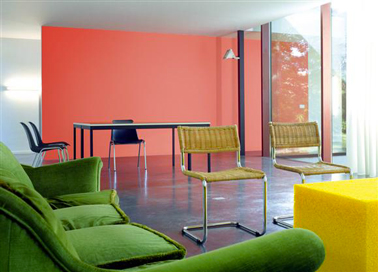 une peinture salon de couleur orange associé à un canapé couleur vert gazon et un sol en béton ciré gris anthracite, une harmonie de couleurs toniques pour la déco d'un salon contemporain 