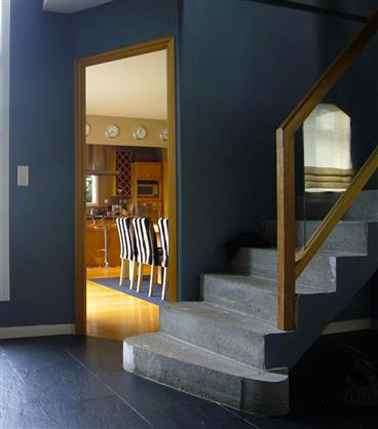 Couleur peinture entrée bleu canard escalier en béton gris Une peinture d'un bleu profond dans l'entrée pour mettre en valeur les couleurs chaudes de la salle à manger. Les boiseries et la rampe d'escalier en bois introduisent l'harmonie de jaunes et bois doré du séjour