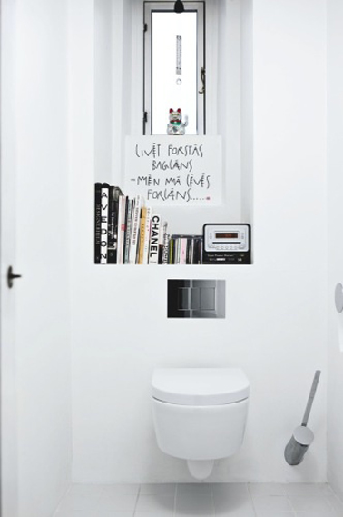 Peinture WC couleur blanc relevée de touches de noir avec les éléments déco, une décoration wc facile à réaliser en blanc et noir. Cuvette wc et murs blanc. Le rebord de la fenêtre est transformé en petite bibliothéque pour accueillir quelques livres aux couvertures noires et blanches