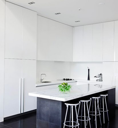 Une cuisine aux grands placards blancs et îlot central gris anthracite moderne et zen Loin d'être excentrique cette cuisine préfère jouer la carte du minimalisme chic en blanc. Les grands meubles aux façades blanches déterminent le volume de la pièce pendant que le sol et l’îlot central anthracite ramènent un contraste structurant l’espace. Lumineuse et simple dans sa déco, cette cuisine n’a pas besoin d’en faire plus pour être une pièce où il fait bon mijoter de bons petits plats.
