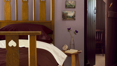 Ambiance cocooning dans la chambre avec des murs d'un doux  violet mat  mis en valeur avec une peinture prune pour les boiseries