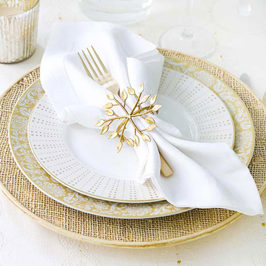 Un pliage serviette pour Noël avec rond de serviette doré agrémenté d'une petite fleur dorée également. Fourchette insérée dans le pliage