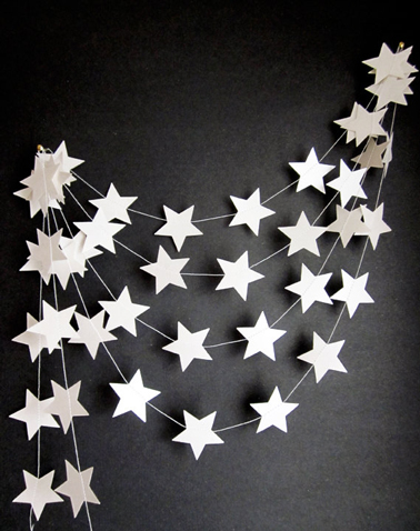 Pour la déco du mur ou du sapin de Noël, Une guirlande de Noël à réaliser soi-même avec des étoiles découpées dans du carton blanc et collées sur du fil de nylon ou de la laine blanche