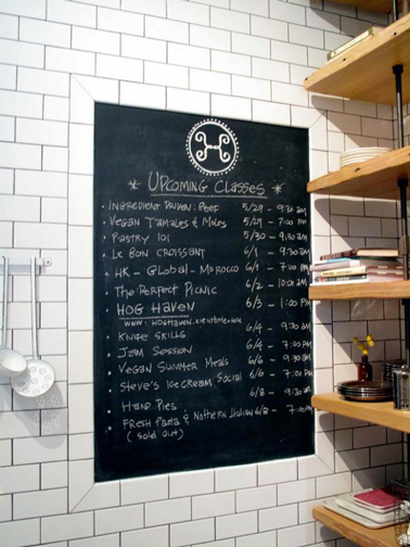 Tableau de peinture noir intégré dans mur de cuisine en carrelage blanc
