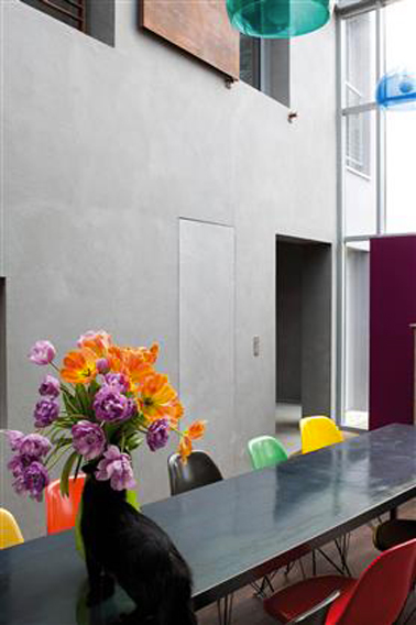 Le gris et noir pour la décoration de cette salle à manger d'une architecture moderne. Les chaises de couleur vives et les suspensions dynamise l'ensemble