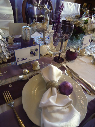 déco table de Noël en violet et ivoire avec nappe et accumulation de chemin de table violet. Assiettes et serviettes blanc ivoire
