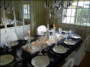 Déco table de Noël avec nappe noire, vaisselle porcelaine ivoire et chemin de table avec neige artificielle blanche