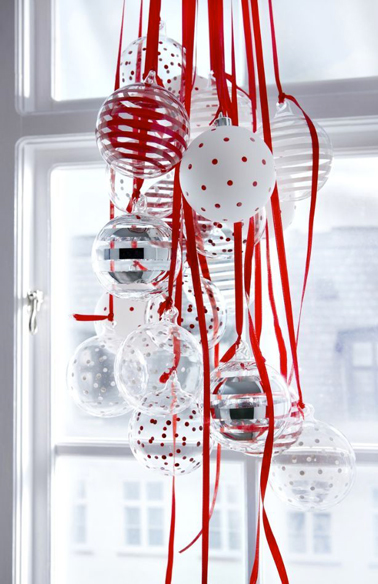 Décoration fenêtre pour Noël avec une suspension de boules de Noël blanches et rouge et transparentes accrochées avec du ruban de satin rouge 