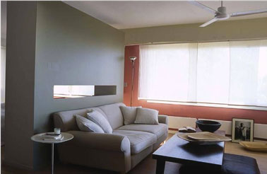 Une décoration de salon gris très élégante avec un pan de mur gris métal pour une ambiance contemporaine avec une touche de orange, des couleurs qui renforcent l'architecture de la pièce