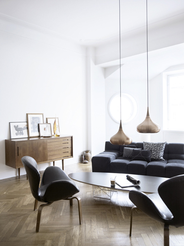 deco salon minimaliste pour une ambiance zen avec un mobilier vintage, canapé et fauteuil cuir noir, grandes suspensions en cuivre