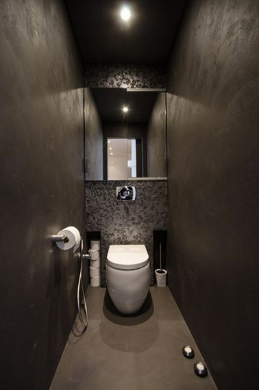 Déco toilettes design avec murs en stuc gris taupe, papier métallisé gris cuvette suspendue blanche, au sol un béton ciré couleur taupe