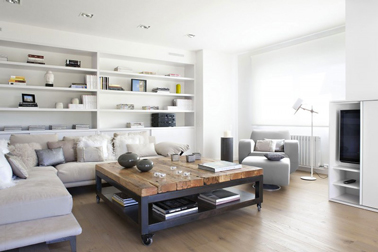 Ambiance zen avec des couleurs salon en dégradé de peinture gris et blanc avec grand canapé d'angle gris perle, table basse esprit industriel en bois et métal. Le fond de la bibliothèque intégrée dans le mur reprend le gris du canapé. 