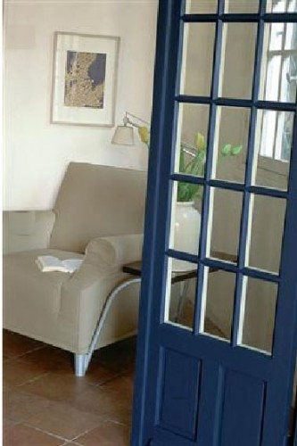 salon harmonie de blanc gris et bleu intense peinture Tollens Une décoration de salon travaillée en contraste avec une peinture murale en gris blanc, un fauteuil dans un doux ton de gris mastic. Le bleu intense de la peinture de la porte crée un joli contraste