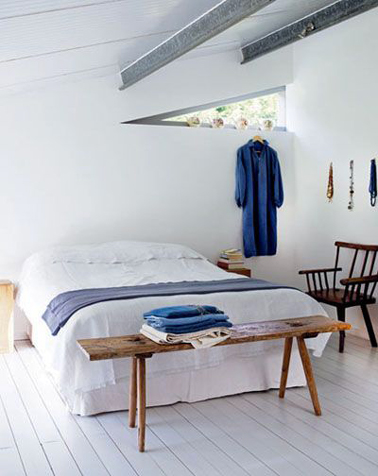 Peu de meubles, des touches de bleu pour une ambiance paisible dans une chambre blanche d'une maison de bord de mer