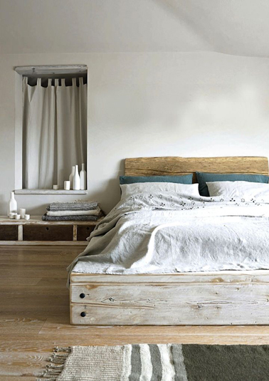 L'intimité d'une chambre grise sous mansarde rendue confortable avec un superbe lit en bois flotté fabriqué avec des planches de récup. La tête de lit est lasurée bois blond pour faire écho à la teinte du parquet bois