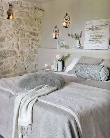 Pour la déco de cette chambre, un dégradé de gris pastel et ivoire qui s'harmonise avec le mur en pierres apparentes. Le mur de la tête de lit est recouvert d'un enduit décoratif gris perle aspect mat.