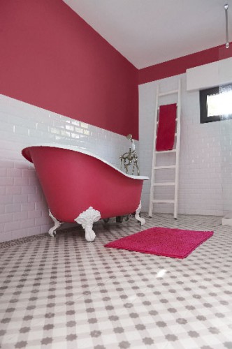 Lorsque la couleur de peinture sert à redonner vie à une salle de bain dont on veut conserver le charme de l'ancien, c'est efficace ! Ici c’est un Bougainvillier, une teinte de rose du nuancier Zolpan qui dynamise la faïence murale d’un blanc éclatant. Profitant de l’occasion, la baignoire îlot enveloppe l’extérieur de sa coque de la même couleur intense.