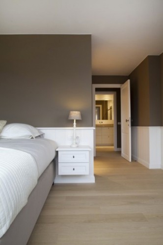 Déco de chambre taupe et blanc pour une ambiance zen dans un style épuré. La peinture taupe, couleur oh combien sereine est mise en contraste avec le blanc pur retenu pour peindre les soubasssements. En harmonie, le couvre sommier dans un tissu taupe clair et le drap gris perle forment un dégradé de couleurs qui trouve son écho avec les couleurs du couloir