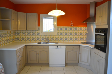 Pour repeindre les meubles de la cuisine rustique c'est la peinture pour meuble de cuisine couleur tourterelle GripActiv V33 qui est choisie pour s'harmoniser avec la couleur du carrelage de la crédence et le rouge de la peinture murale