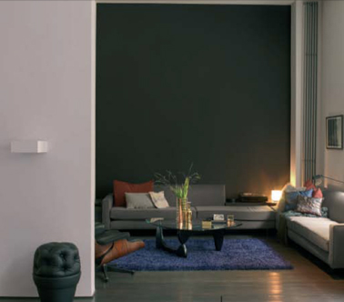 La couleur taupe sur un seul mur du salon derrière le canapé, un gris perle pour les autres murs pour une déco de salon design et cocooning. Pour illuminer l’espace, un tapis bleu canard. Peinture Astral