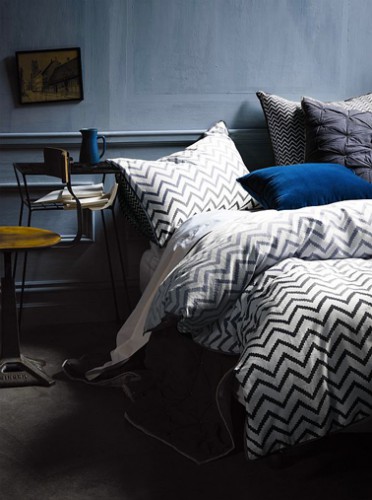 Une peinture chambre couleur délavé et des tons de bleu marine à bleu klein pour le linge de lit uni et à rayures. La table de chevet jaune moutarde révèle la subtilité des jeux de couleurs bleu