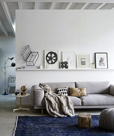 Déco salon gris avec une peinture blanche sur la cloison de séparation qui révèle le gris perle du canapé. au sol, le tapis bleu canard illumine les couleurs neutres dominantes 
