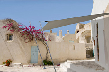 Une voile d'ombrage rectangulaire couleur taupe placée devant la porte d'entrée de la maison pour filtrer les rayons du soleil. Photo Leroy Merlin.